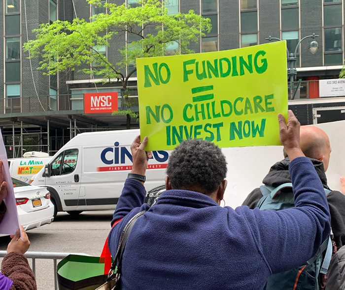 no funding no childcare woman holding a poster