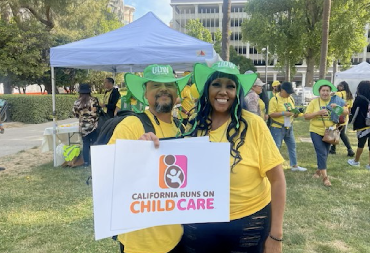 Two people holding California runs on child care sign
